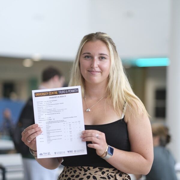 A photo of Lucy, she is wearing a black top and is holding her results up in front of her.