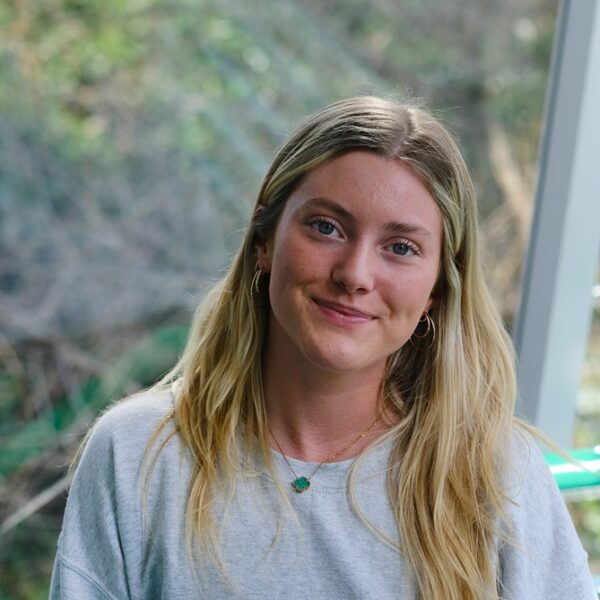 A photo of Sennen, she is wearing a grey sweatshirt and has blonde hair. She smiles at the camera.