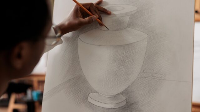 Closeup of man holding pencil practicing pencil shading techniques, being focused on process of sketching