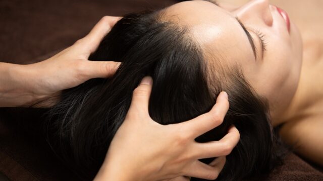 Closeup of hands massaging a person's scalp.