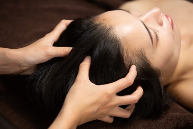 Closeup of hands massaging a person's scalp.
