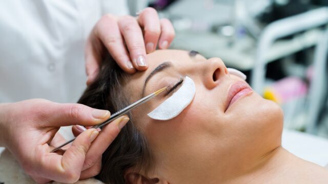 Woman having eye lashes tinted in beauty salon.