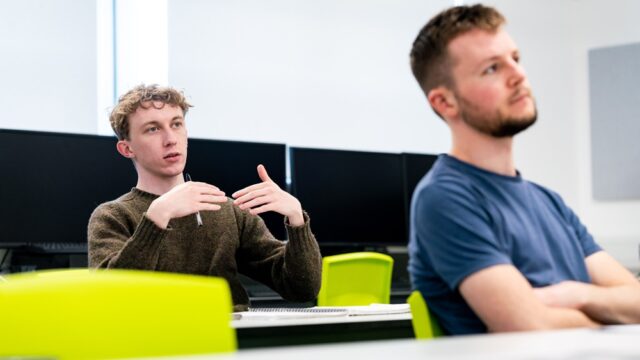 Two students sit in a GTR and look towards the front of the class.