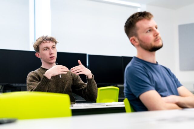 Two students sit in a GTR and look towards the front of the class.