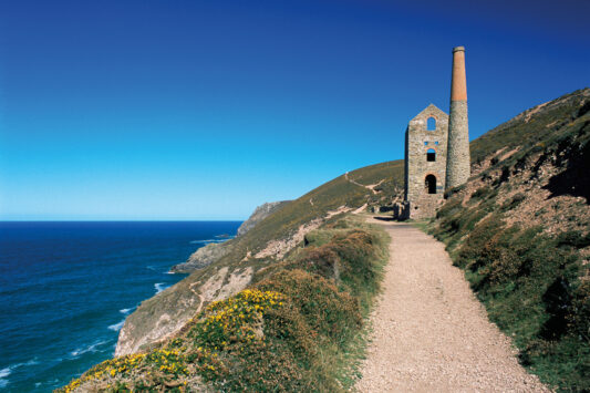A picture of a cornish engine house on a coast path on a sunny day.