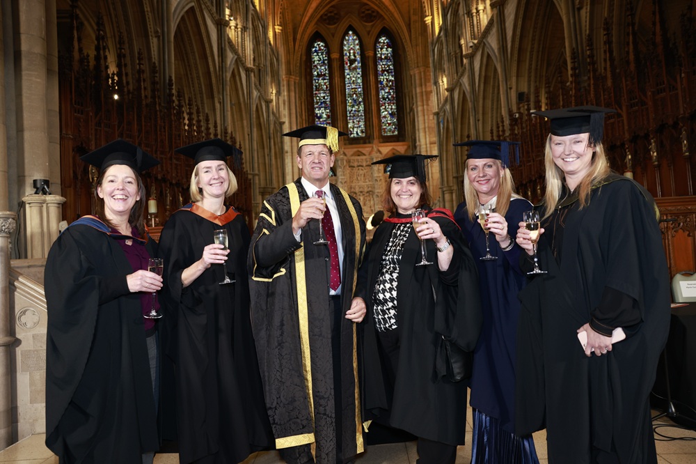 A photo of Martin Tucker and senior colleagues in Truro Cathedral raising a glass to the camera. They are all wearing ceremonial robes.