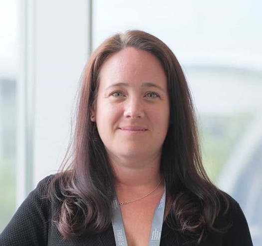 A photo of Emily Myatt. She is wearing a black dress and a staff lanyard.