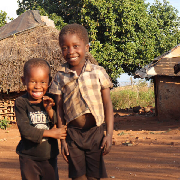 Two young Eswatini boys smile and laugh as they look at the camera.