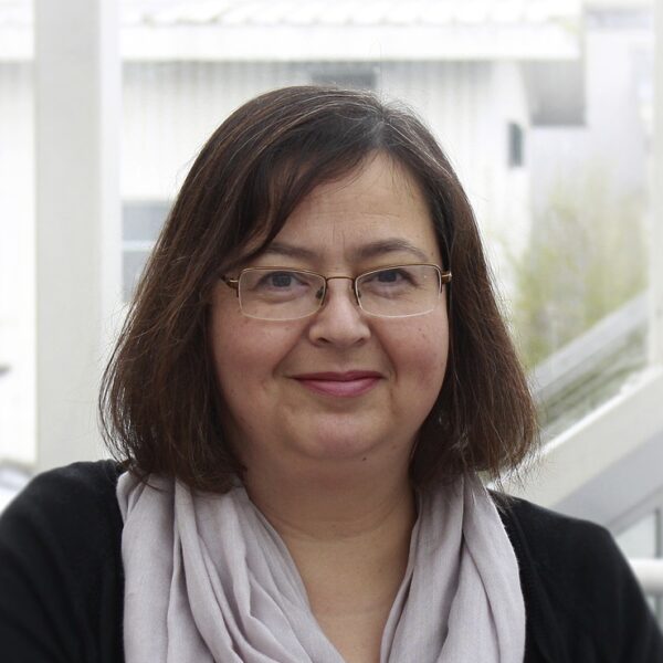 A photo of Tracy Triggs smiling at the camera wearing a grey skirt.