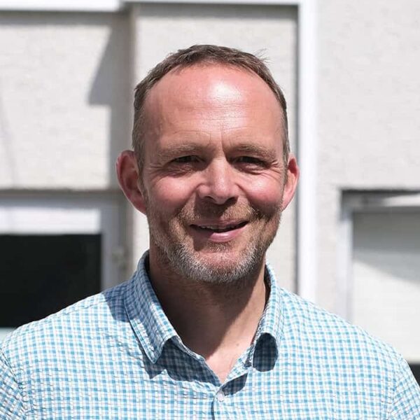 A photo of IB Diploma Coordinator, Paul Gill. Paul is wearing a check shirt with a pen in his pocket.