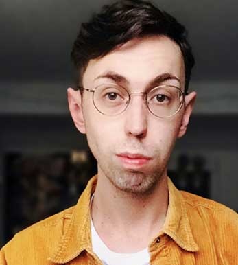 A photo of Roland Bray, he is wearing a golden coloured shirt and white t shirt.