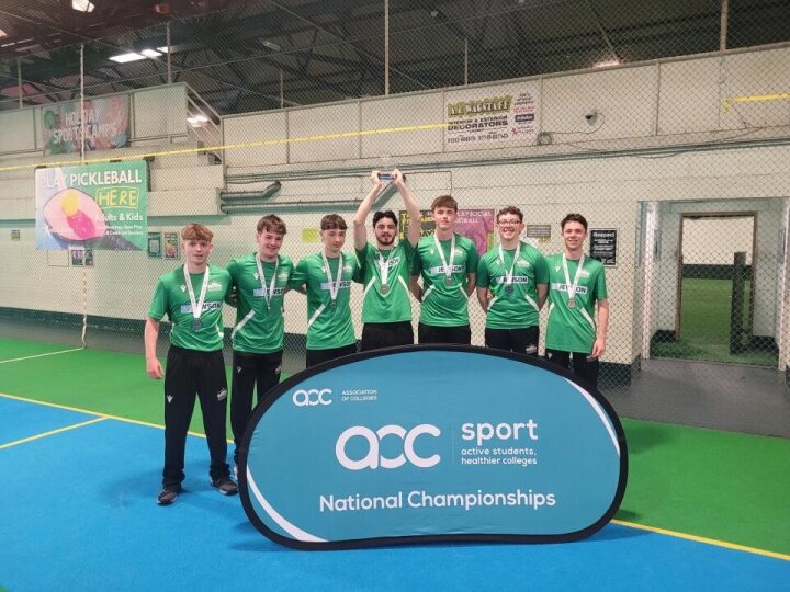 A group of students with their arms around each other in a sports hall.