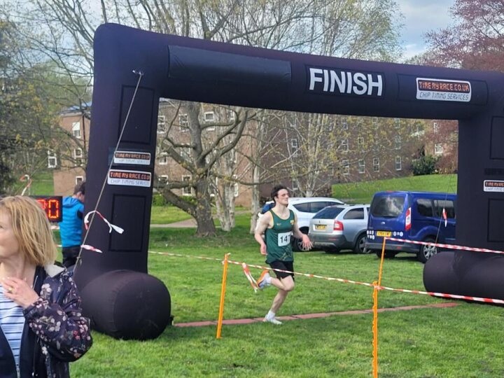 A runner crossing a finish line in a green area.