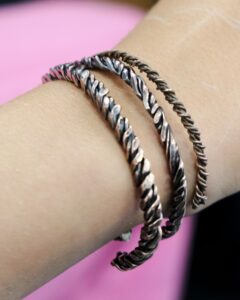 Three metal bracelets on a wrist.