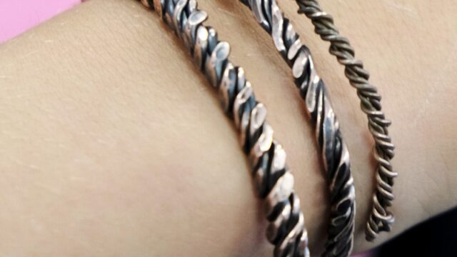 Three metal bracelets on a wrist.