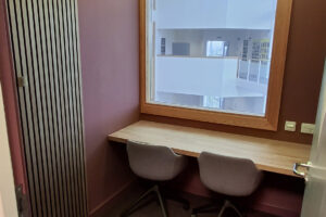 A small purple coloured room with two chairs, a window and a table.