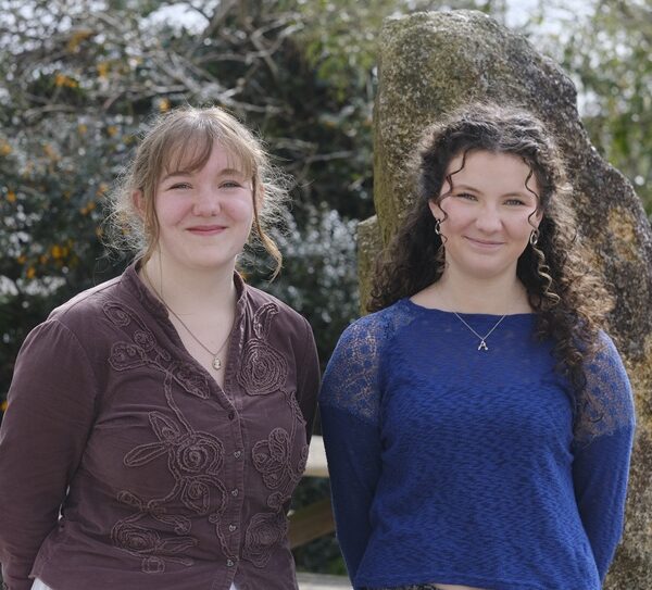Aoife and Ruth stand side by side with a large rock behind them.