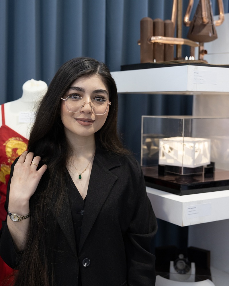 A student stands in front of artwork at the Truro College Art Exhibition.