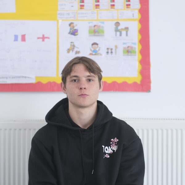 Rowan sat in a classroom wearing a dark hoodie.