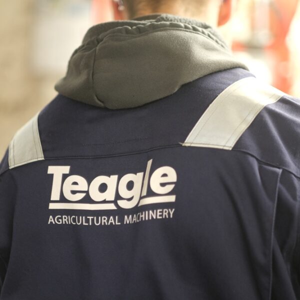 The back of a worker's jacket that says Teagle Agricultural Machinery.