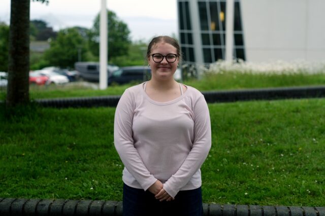 Edie Newman stood outside at the College with her hands in front of her.
