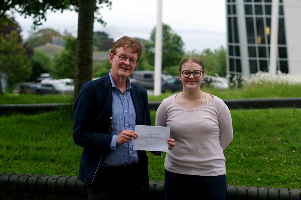 Colin Fell and Edie Newman holding up an award outside the college.