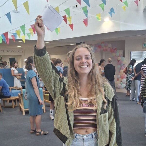 Amelia holding her results up in the air over her head in triumph.