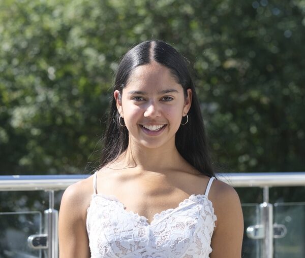 Amelie stood outside at Penwith College. She is wearing a white top and has long dark hair.