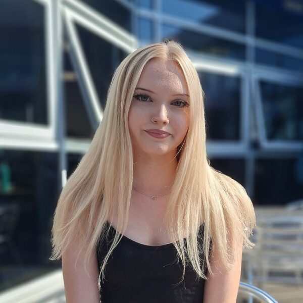 Annalisa sat outside on a metal bistro chair wearing a black top.