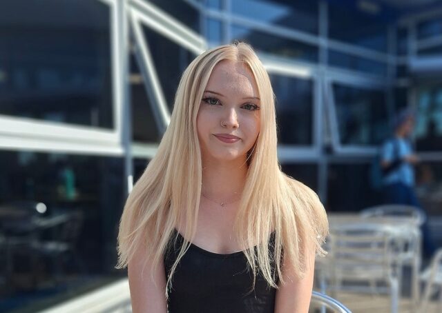 Annalisa sat outside on a metal bistro chair wearing a black top.