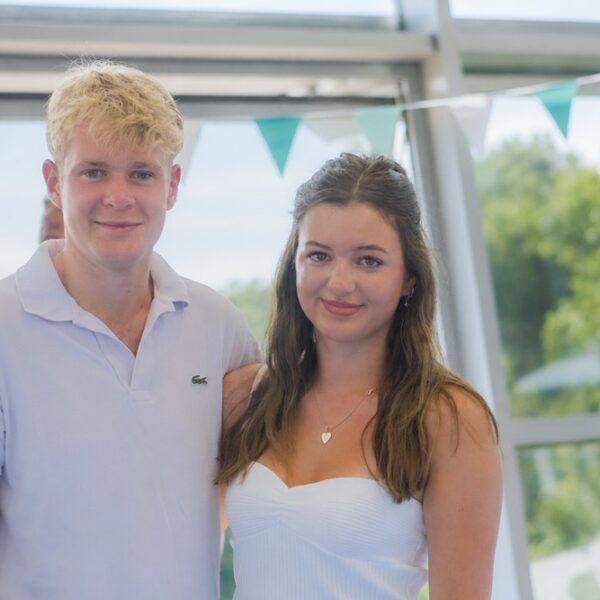 Archie and Cora stood side by side with blue bunting behind them.