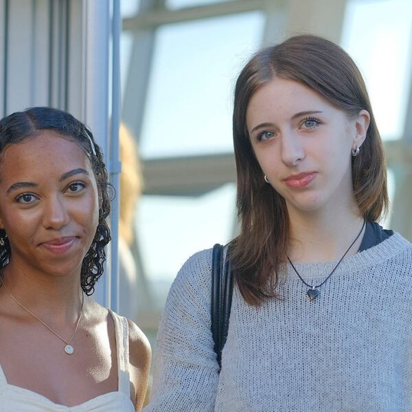Millie and Mareme stood in front of a large window smiling at the camera.