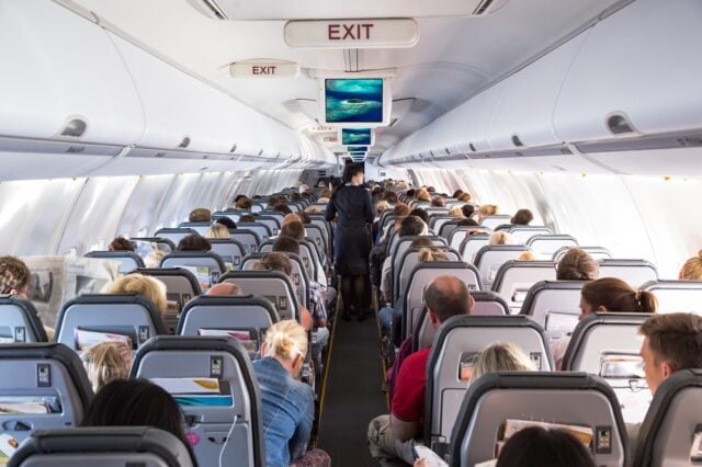 Inside view on passenger and cabin crew people on an airline airplane during flight to vacation. Transportation tourism aviation concept