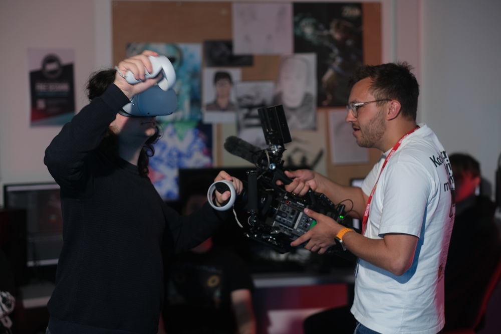 A cameraman points a camera towards a student using a VR headset.
