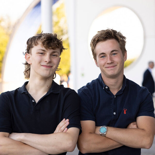 Sam and Luke stood side by side with their arms crossed smiling at the camera.