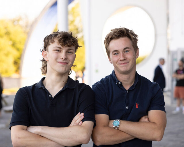 Sam and Luke stood side by side with their arms crossed smiling at the camera.