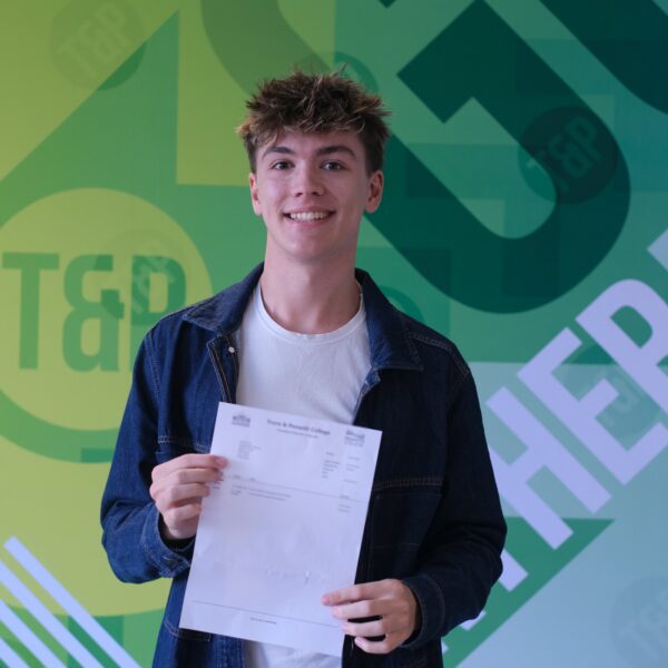 Joel pictured smiling, holding his exam results letter