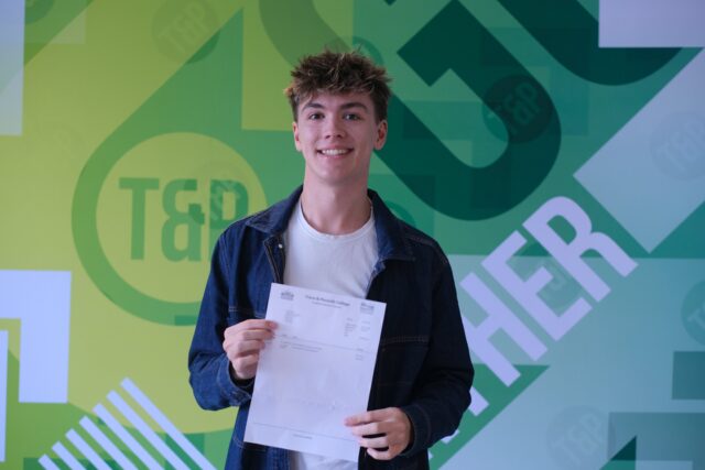 Joel pictured smiling, holding his exam results letter