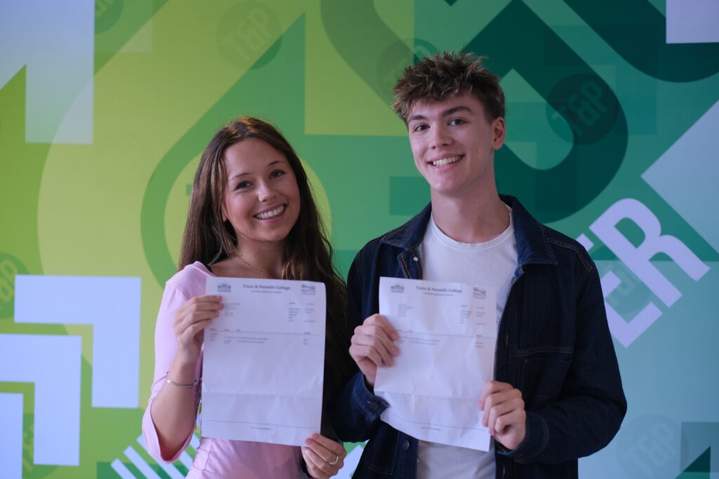 Joel pictured with Grace, both smiling as they hold their exam results letter