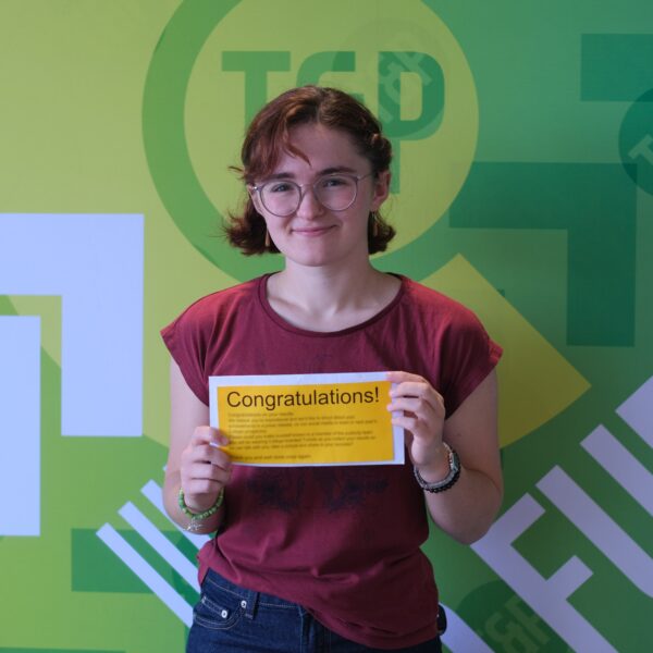 Olivia stands smiling, holding exam results letter
