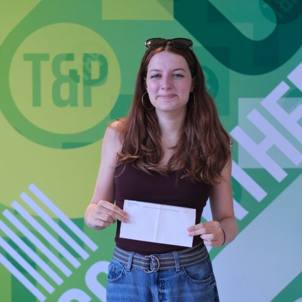 Katie smiles as she hold her exam results letter