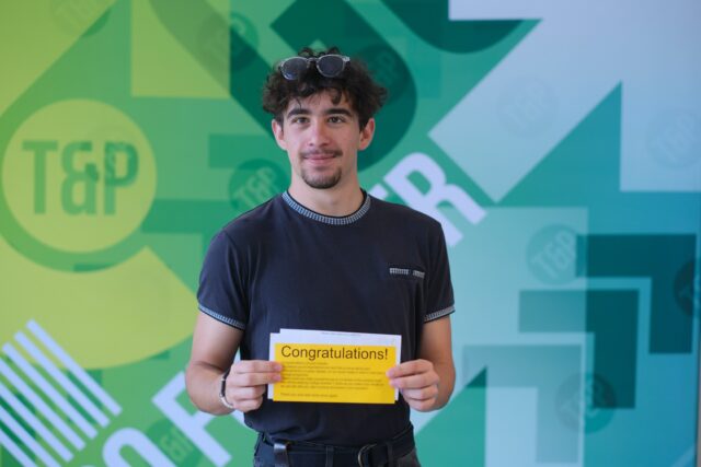 Casey smiles as he holds his results letter