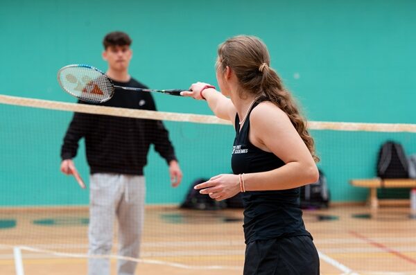 Two students play badminton in one of the College's sports halls.