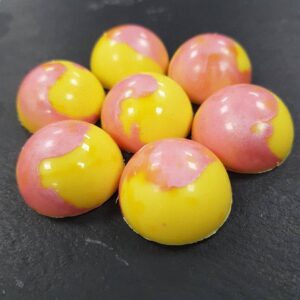 A close-up of paink and yellow sweets on a dark grey slate.