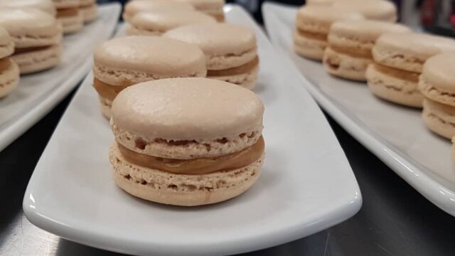 Light brown macarons on white plates.