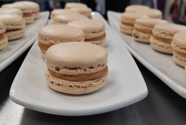 Light brown macarons on white plates.