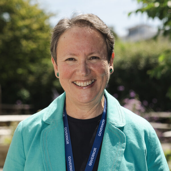 Kay Penney wearing a blue blazer and a black T-shirt stood outside in the sun.