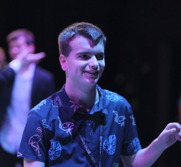 A student in a shirt in a darkened room with purple lighting.