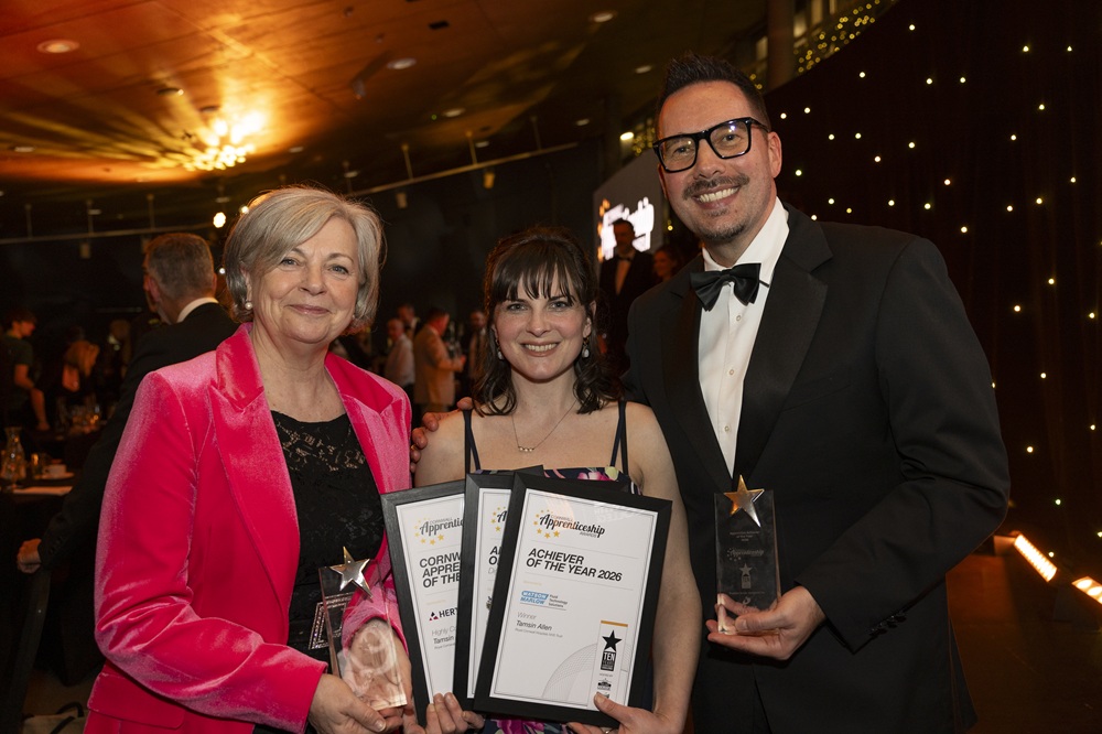 Tamsin Allen holding up certificates and trophies with the presenters of the apprenticeship awards.