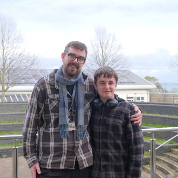 (R-L) Lecturer Joe Sandles stood with his arm around Joe. Both stood outside smiling.